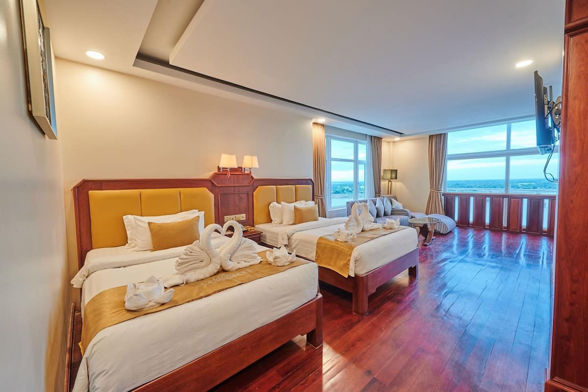 Une chambre d’hôtel avec deux lits, une grande fenêtre et une vue sur le paysage.