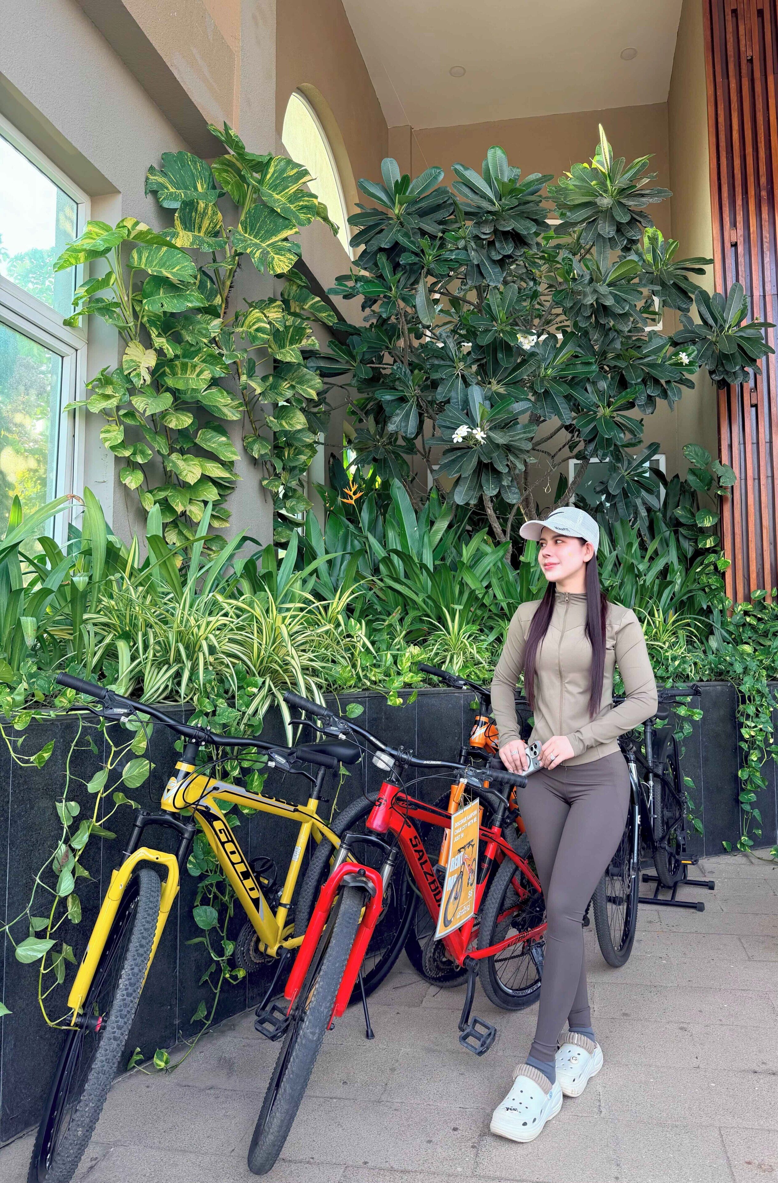Iemand staat naast fietsen, met een groene wand op de achtergrond.