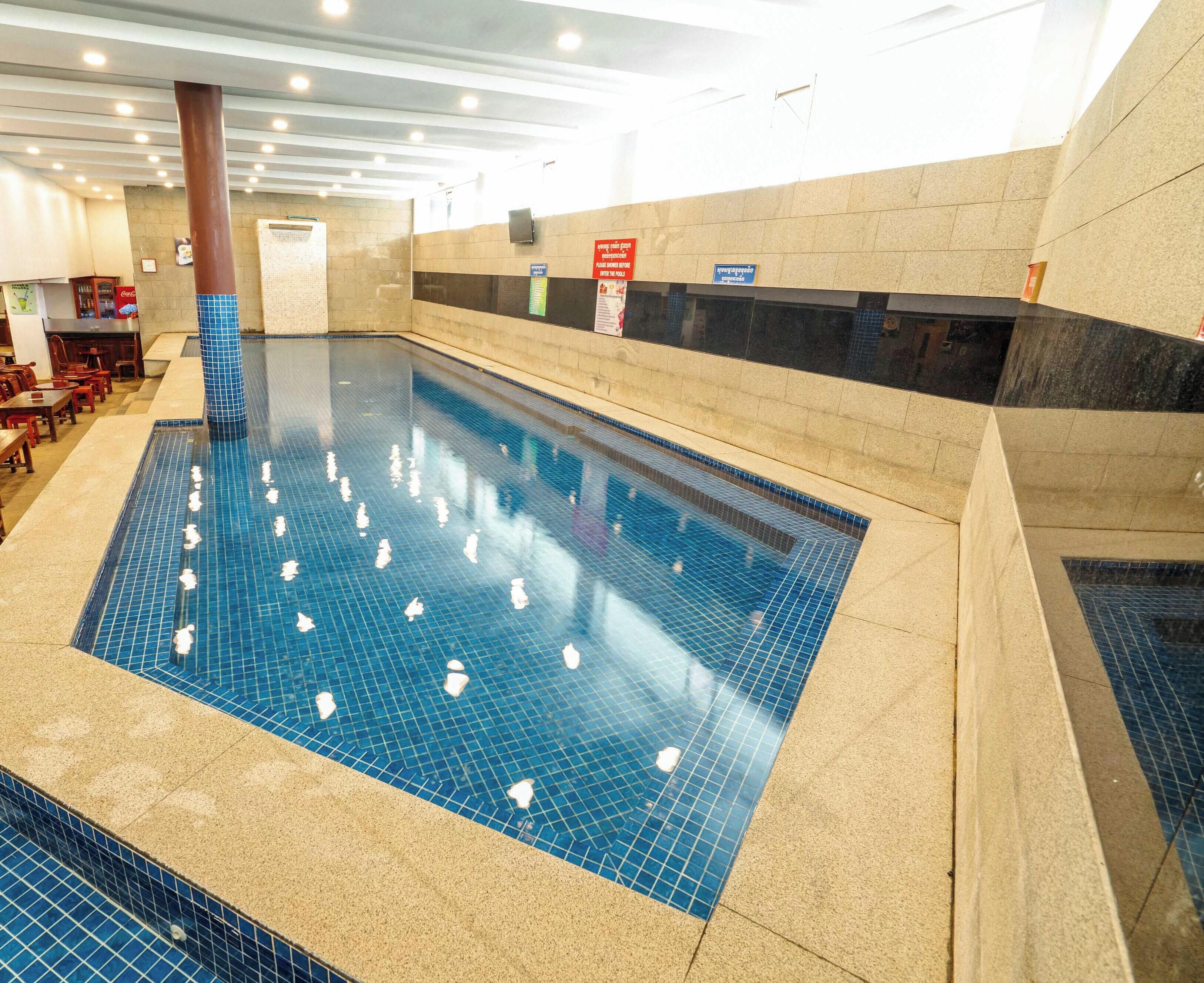 An indoor swimming pool with tiled walls and a clear pool floor.