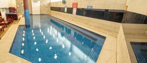 An indoor swimming pool with tiled walls and a clear pool floor.