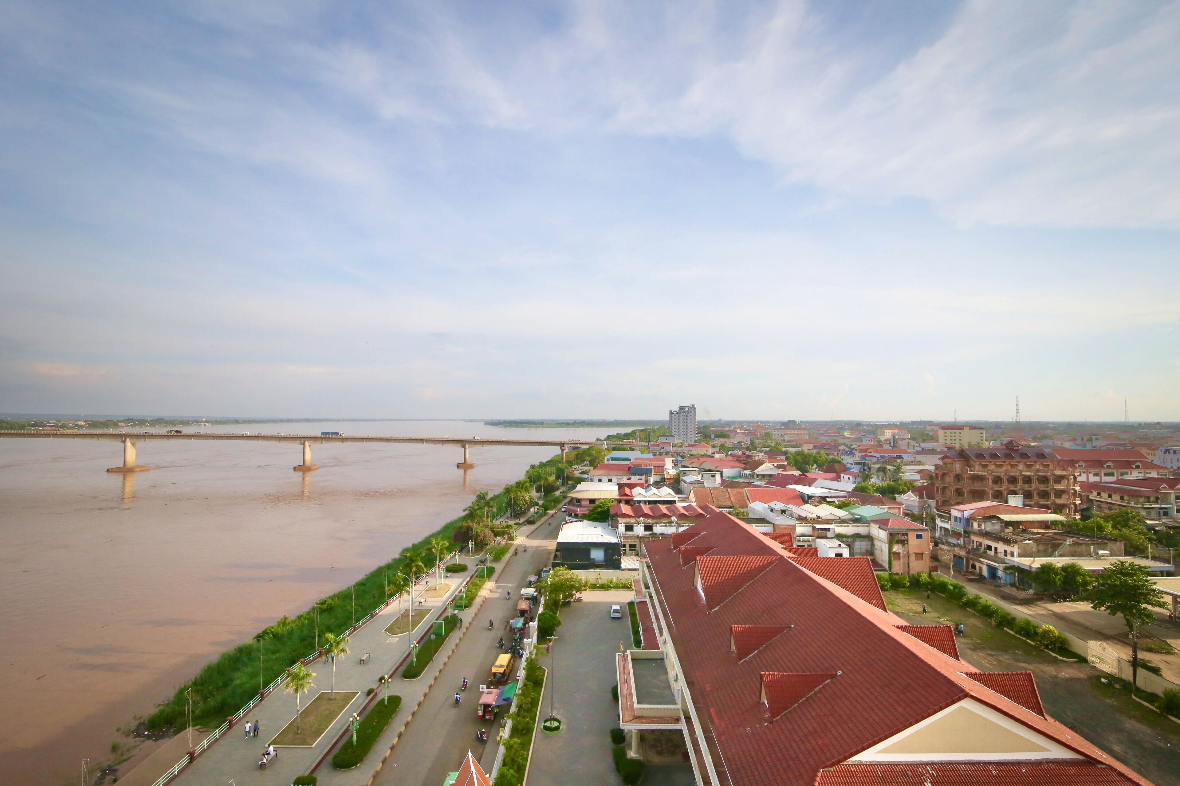 Vista del río con un pueblo, un puente, edificios y una carretera con vehículos.