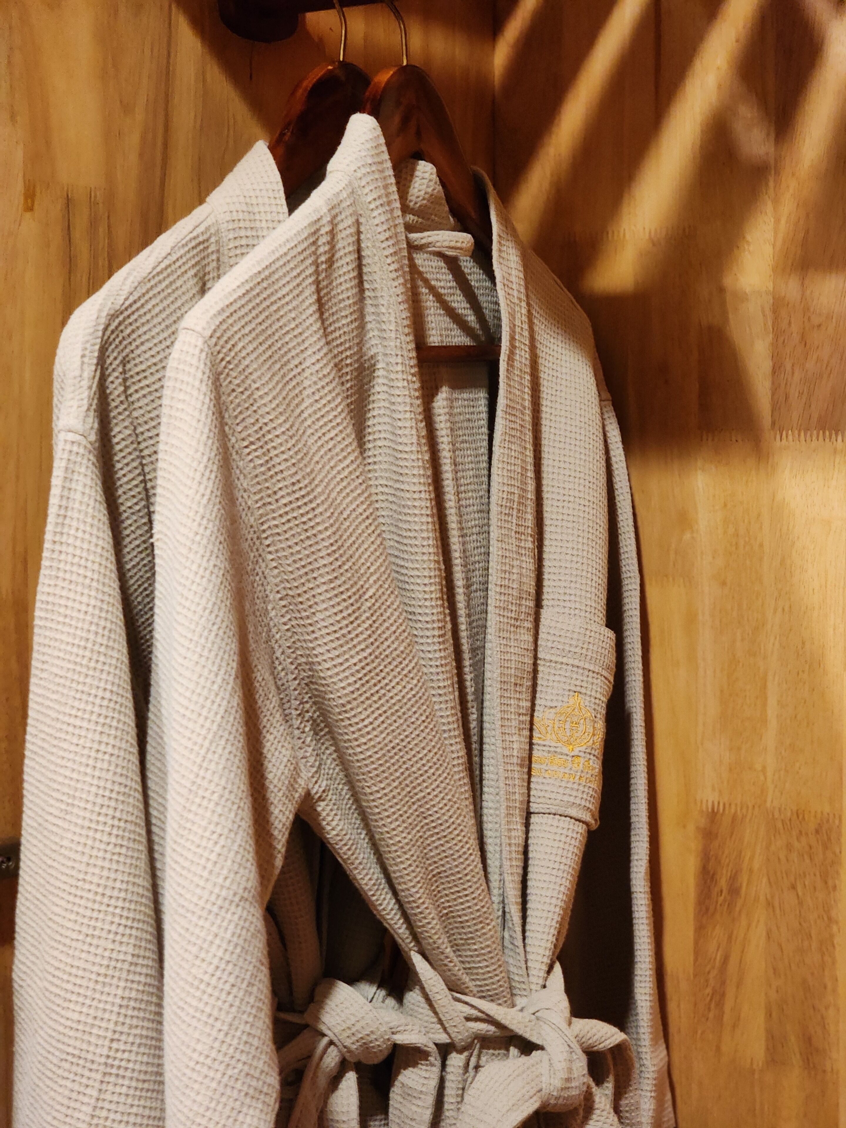 Un albornoz blanco colgado de una percha de madera en una habitación de madera.