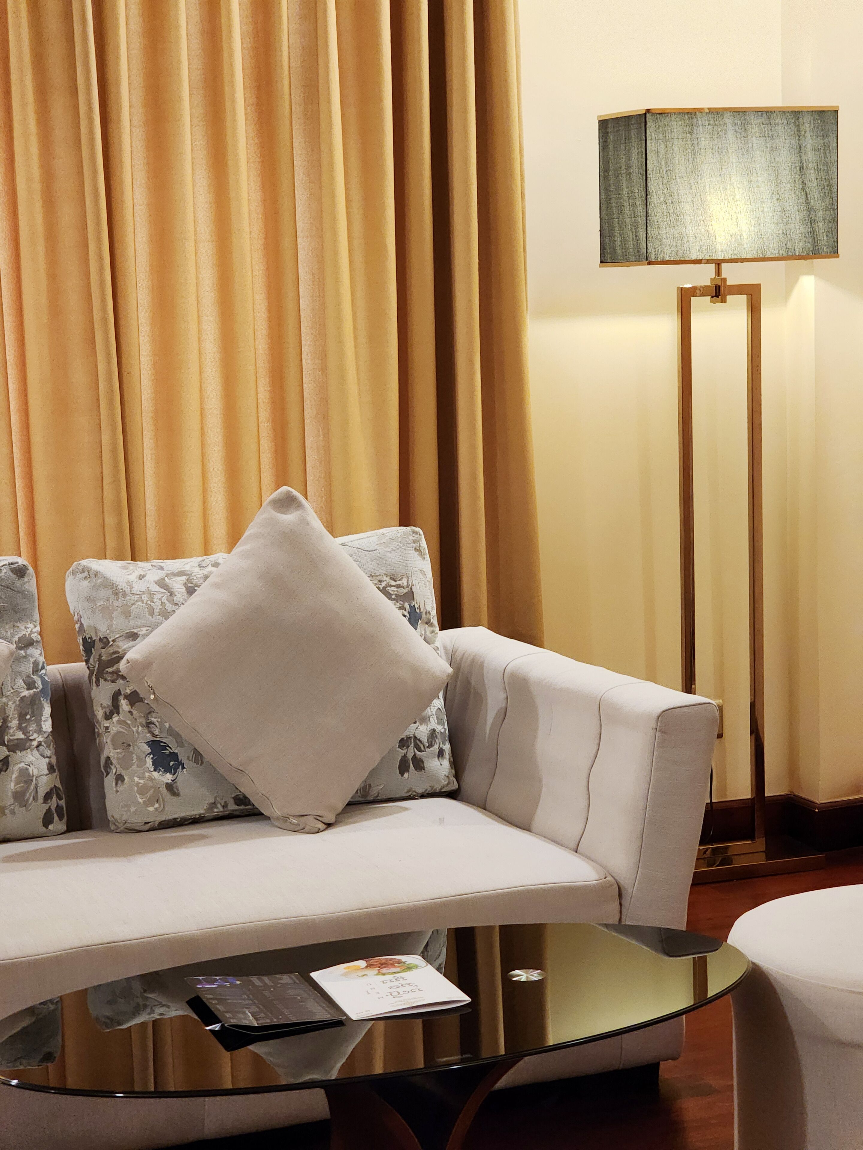 A modern living room with a sofa, a glass coffee table, and a floor lamp.