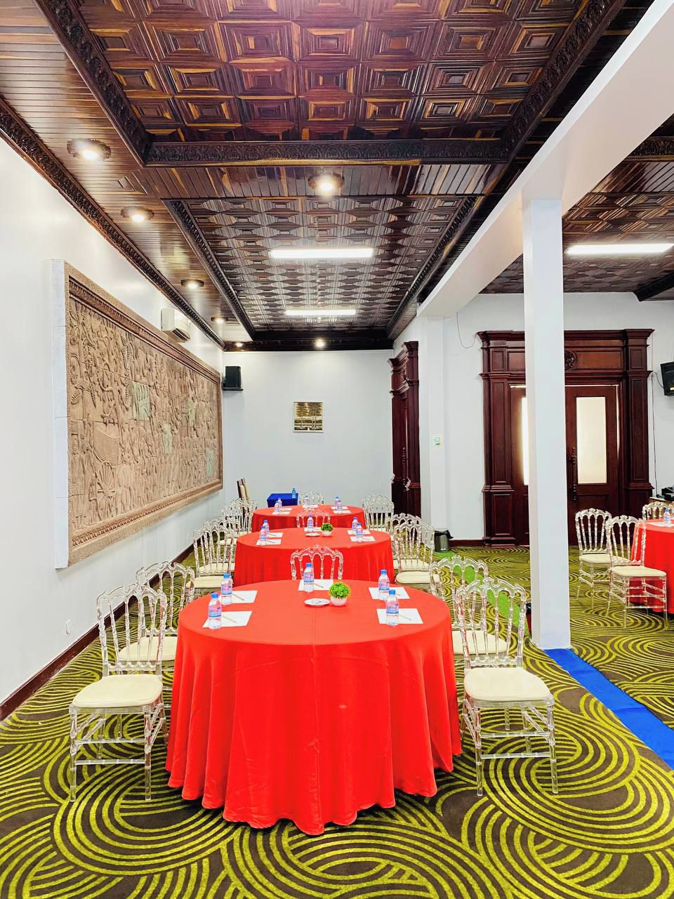 A conference room with round tables, white chairs, and red tablecloths.