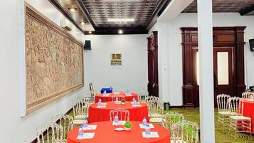 A conference room with round tables, white chairs, and red tablecloths.