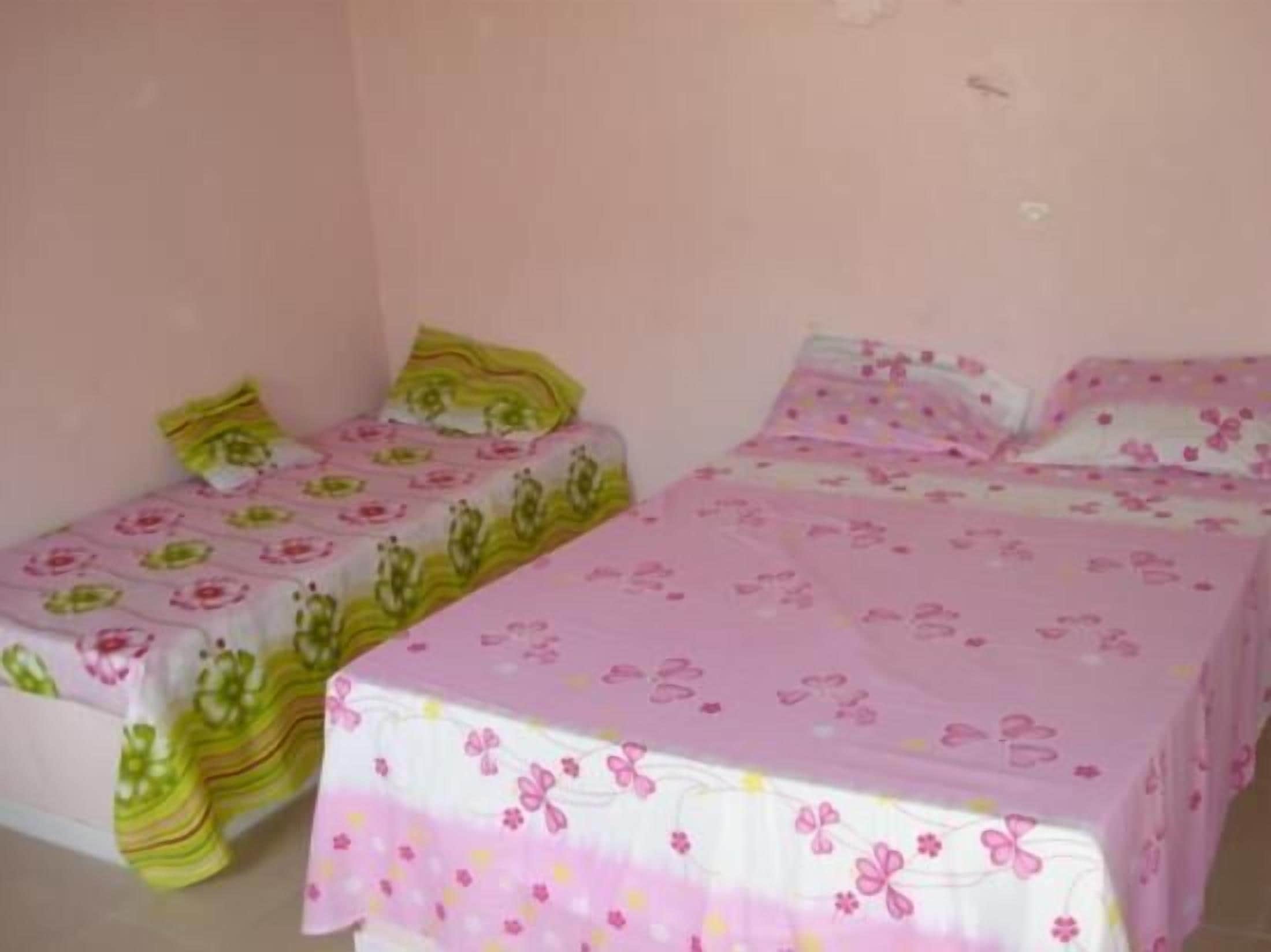 Una habitación pequeña, individual, con dos camas, cada una con ropa de cama estampada con motivos florales.