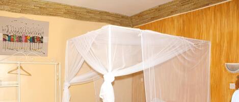 Una habitación con una cama bajo un dosel blanco, una pared de madera y un cuadro enmarcado.