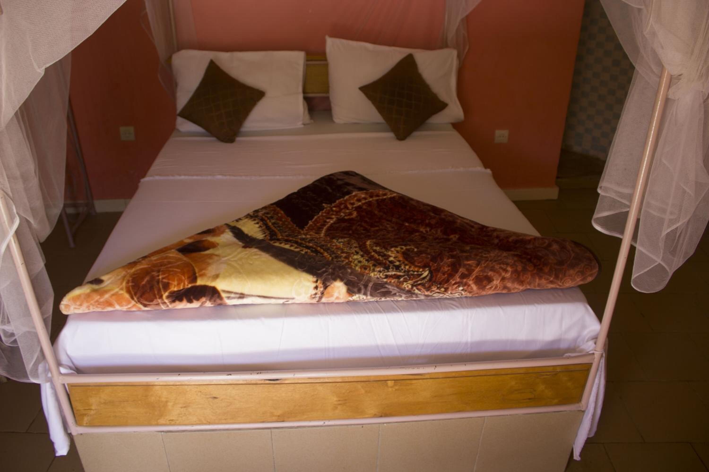 A bed with a canopy, white bedding, and a patterned blanket.