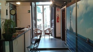 A corridor with a wooden floor, a small table with chairs, a potted plant, and a wall clock. - Residenza Pizzofalcone (Naples)