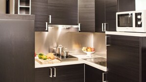 A modern kitchen with dark cabinetry, stainless steel appliances, and a microwave. - Residenza Pizzofalcone (Naples)