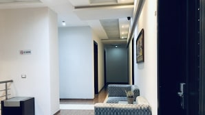 Un hall d’hôtel moderne, avec un panneau « interdiction de fumer », un coin salon doté de meubles recouverts d’un tissu à motifs et une porte sombre.