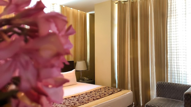 Une chambre d’hôtel avec un lit, une chaise et une fenêtre avec des rideaux.
