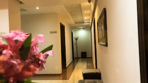 Un couloir d’hôtel avec un panneau « Il est interdit de fumer », un porte-manteau et un banc.