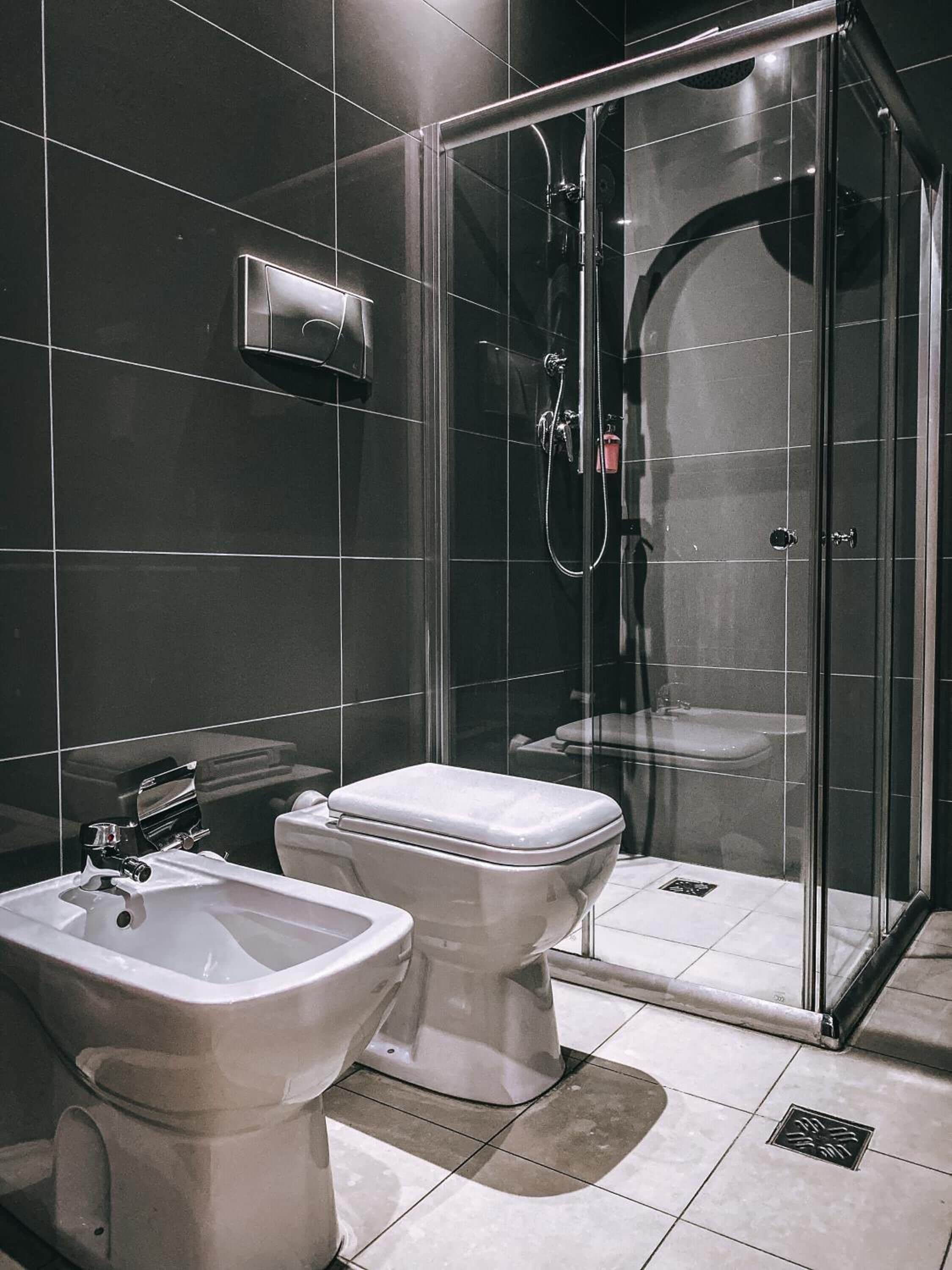 Un baño moderno con ducha envuelta en vidrio, un bidé y un inodoro.