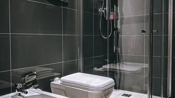 Un baño moderno con ducha envuelta en vidrio, un bidé y un inodoro.