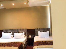 A hotel room with two beds, each with a headboard, a bedside table, and a telephone.