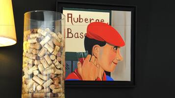 A framed artwork of a person wearing a red hat, next to a glass container filled with wine corks.