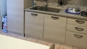 A kitchen with light-colored cabinets, a stainless steel sink, and a countertop with a blue tray. - Nightstars B&B (Mestre)