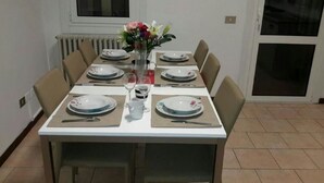 A dining table set for six with plates, cutlery, and a vase of flowers. - Nightstars B&B (Mestre)
