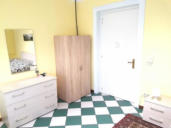 A room with a white dresser, a mirror, a wooden wardrobe, and a checkered floor. - Nightstars B&B (Mestre)