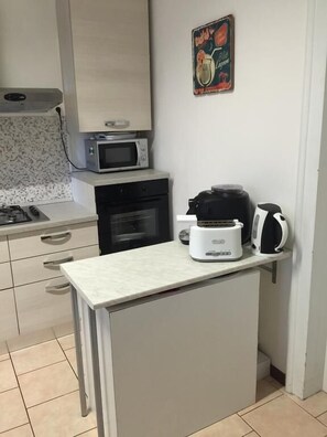 A compact kitchen with a microwave, oven, toaster, and kettle on a countertop. - Nightstars B&B (Mestre)