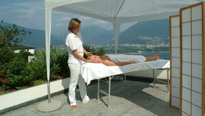 A massage therapy session in a tented area with a scenic mountain view. - Hotel La Campagnola (Gambarogno)