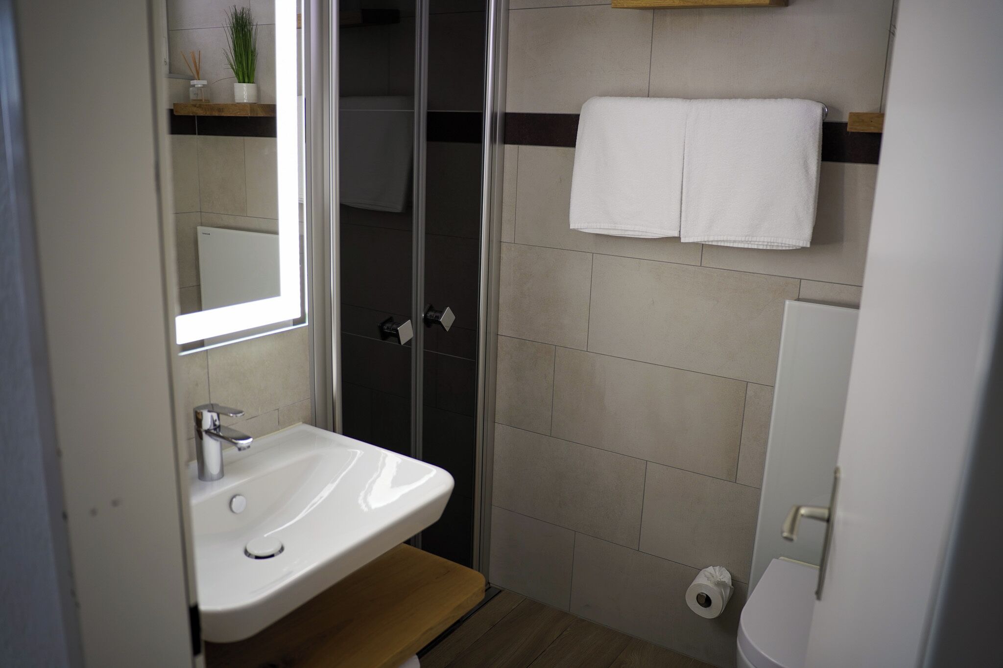 A bathroom with a white sink, a glass shower enclosure, and a toilet.
