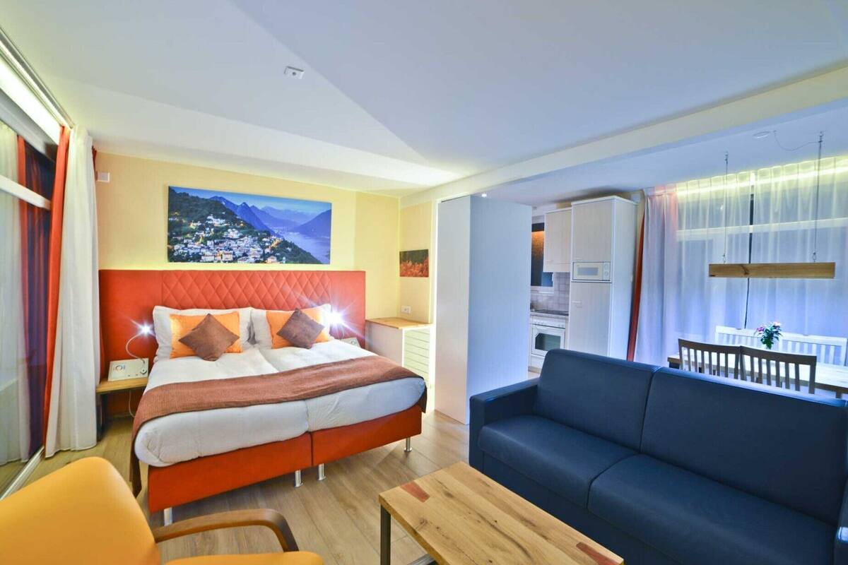 Een hotelkamer met een bed, een bank, een houten tafel en uitzicht op de stad.
