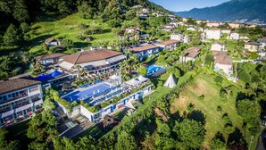 An aerial view of a hotel with a swimming pool, tennis courts, and a restaurant. - Hotel La Campagnola (Gambarogno)