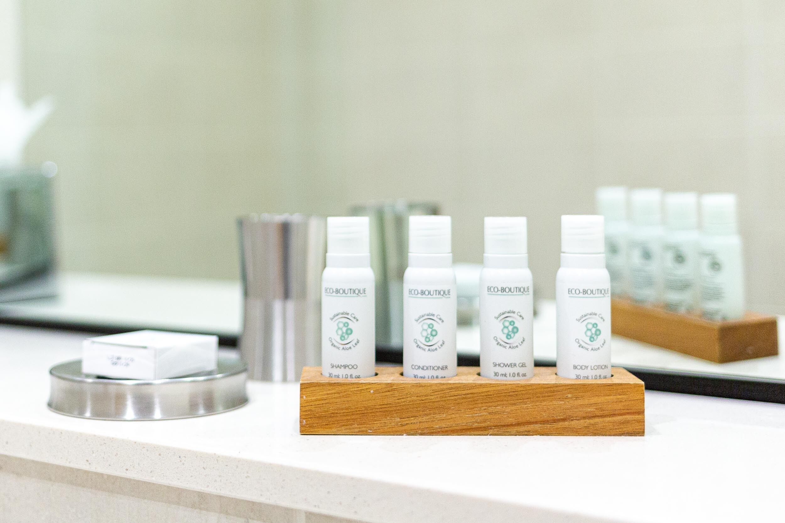 A display of eco-friendly personal care products on a wooden stand in a hotel setting.