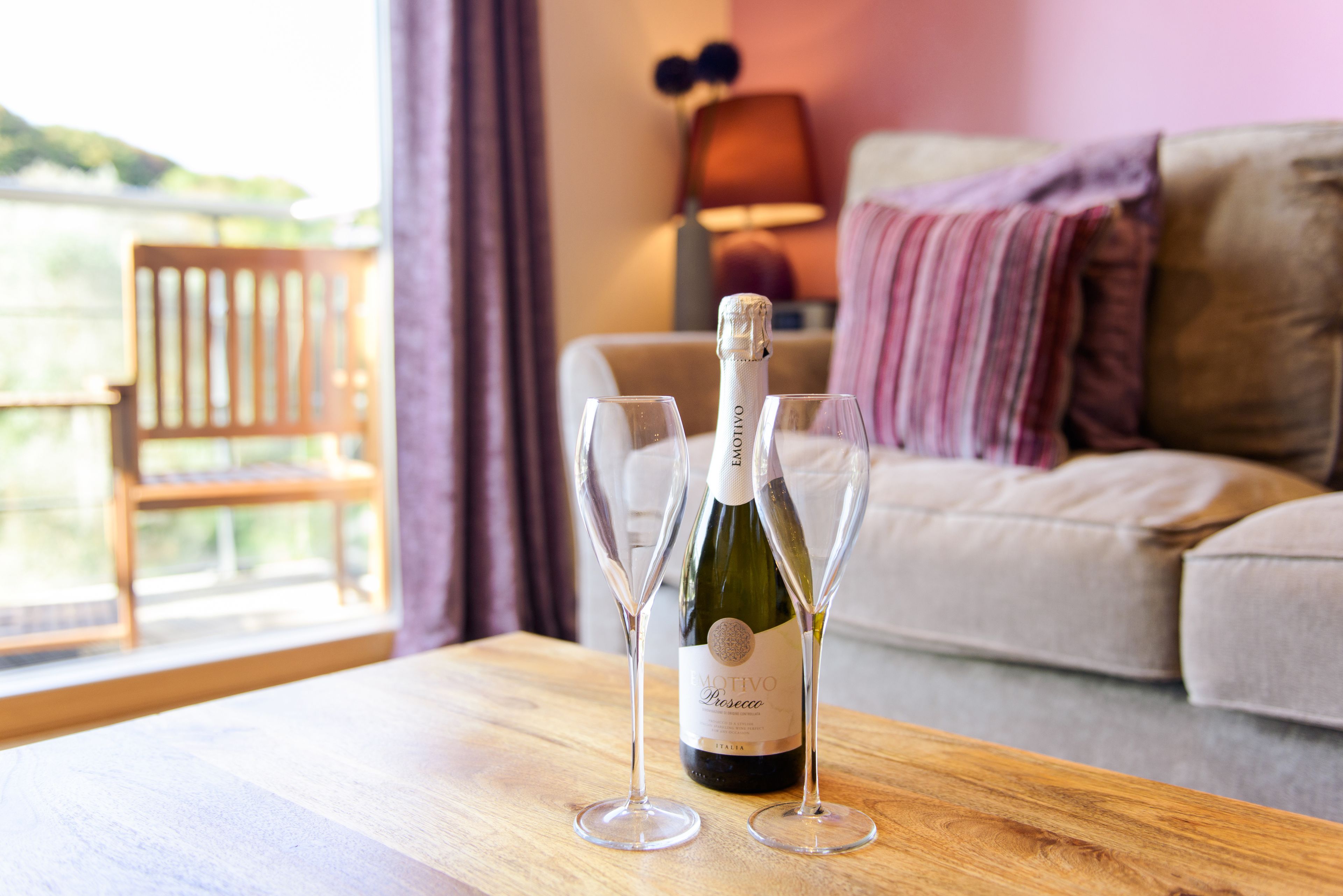 A bottle of Motivo Rosé on a wooden table with two glasses.