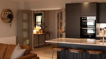 A modern kitchen with a central island, dark cabinetry, and a built-in oven.