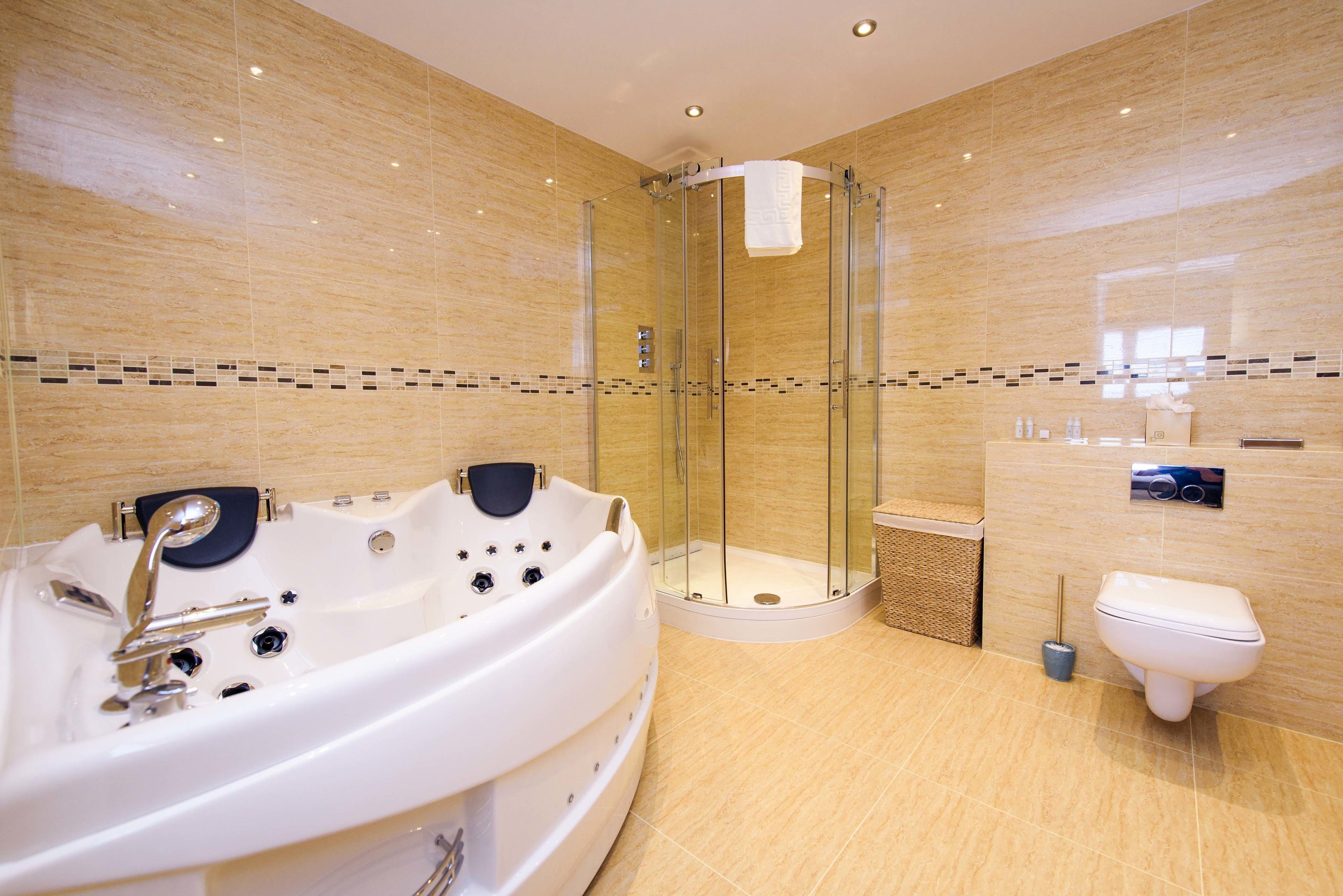 Un baño moderno con ducha envuelta en vidrio, una bañera independiente y un inodoro.