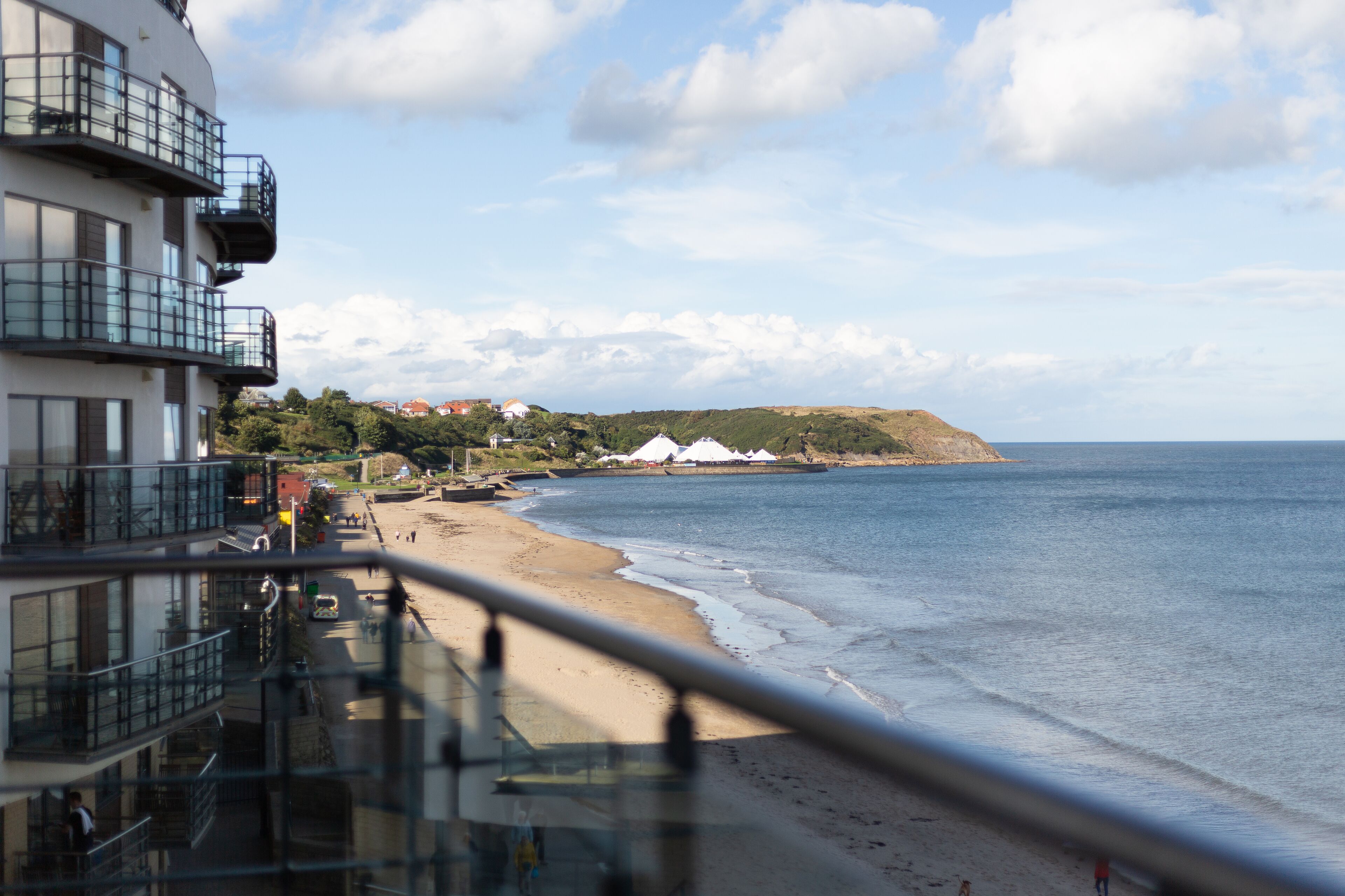 Ein Küstenhotel mit Balkon und Blick auf Strand und Meer.