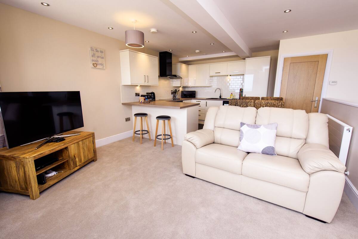 A modern living room with a TV, a sofa, and a wooden coffee table.