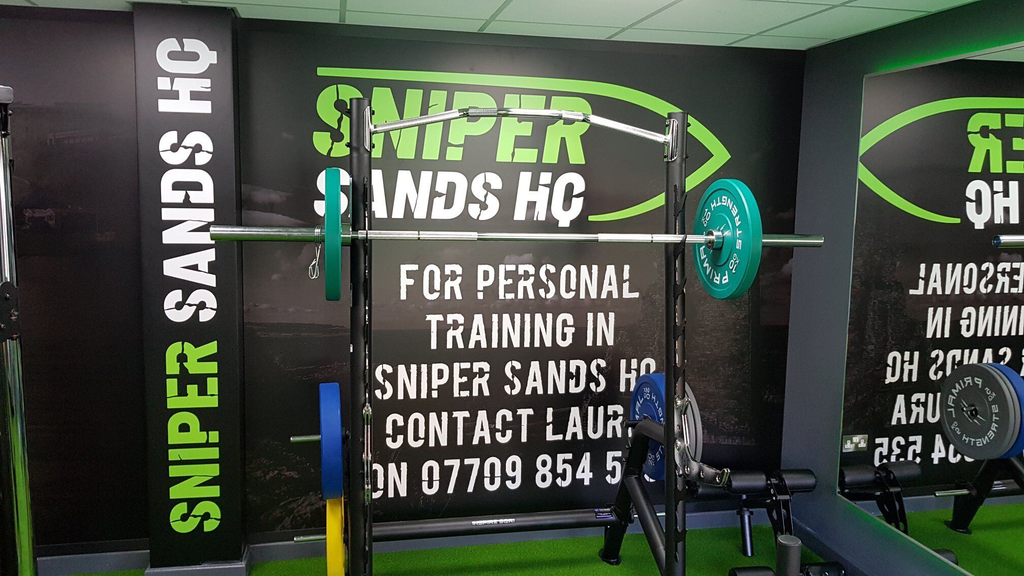Een sportschool met een kleurenschema in zwart en groen, met een halterrek en gewichtsschijven.