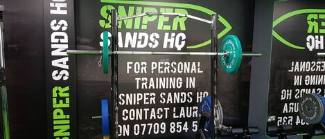 A gym with a black and green color scheme, featuring a barbell rack and weight plates.