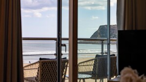 A beach view from a room with a large window, featuring a chair and a table. - The Sands - Sea Front Apartments (Scarborough)