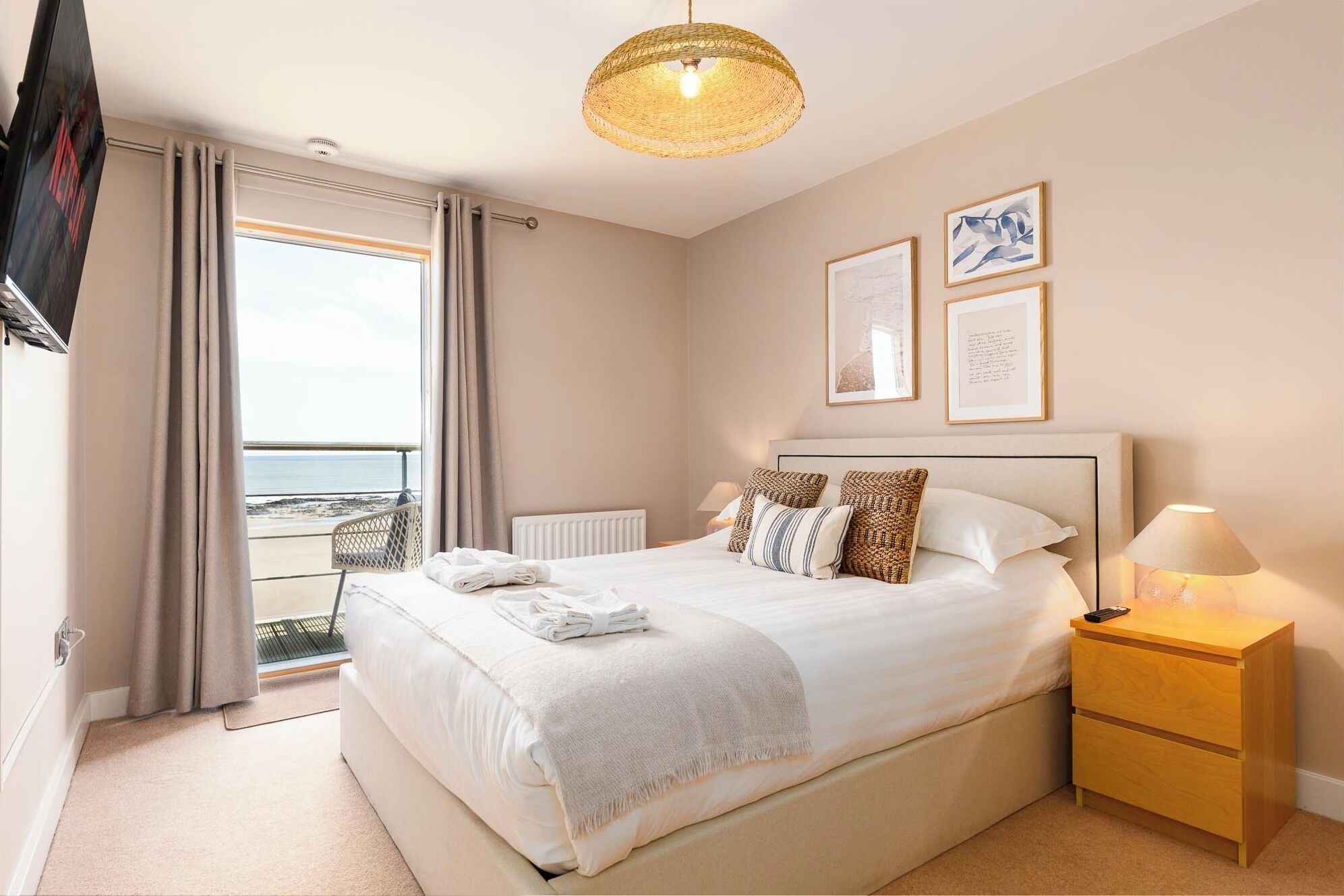 A hotel room with a bed, a bedside table, a lamp, and artwork on the wall.
