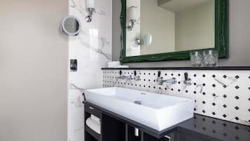 Une salle de bain moderne avec un grand lavabo blanc, des meubles en bois foncé et un miroir à cadre vert.