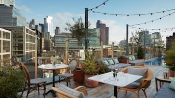 A rooftop terrace with seating, a pool, and a city view.