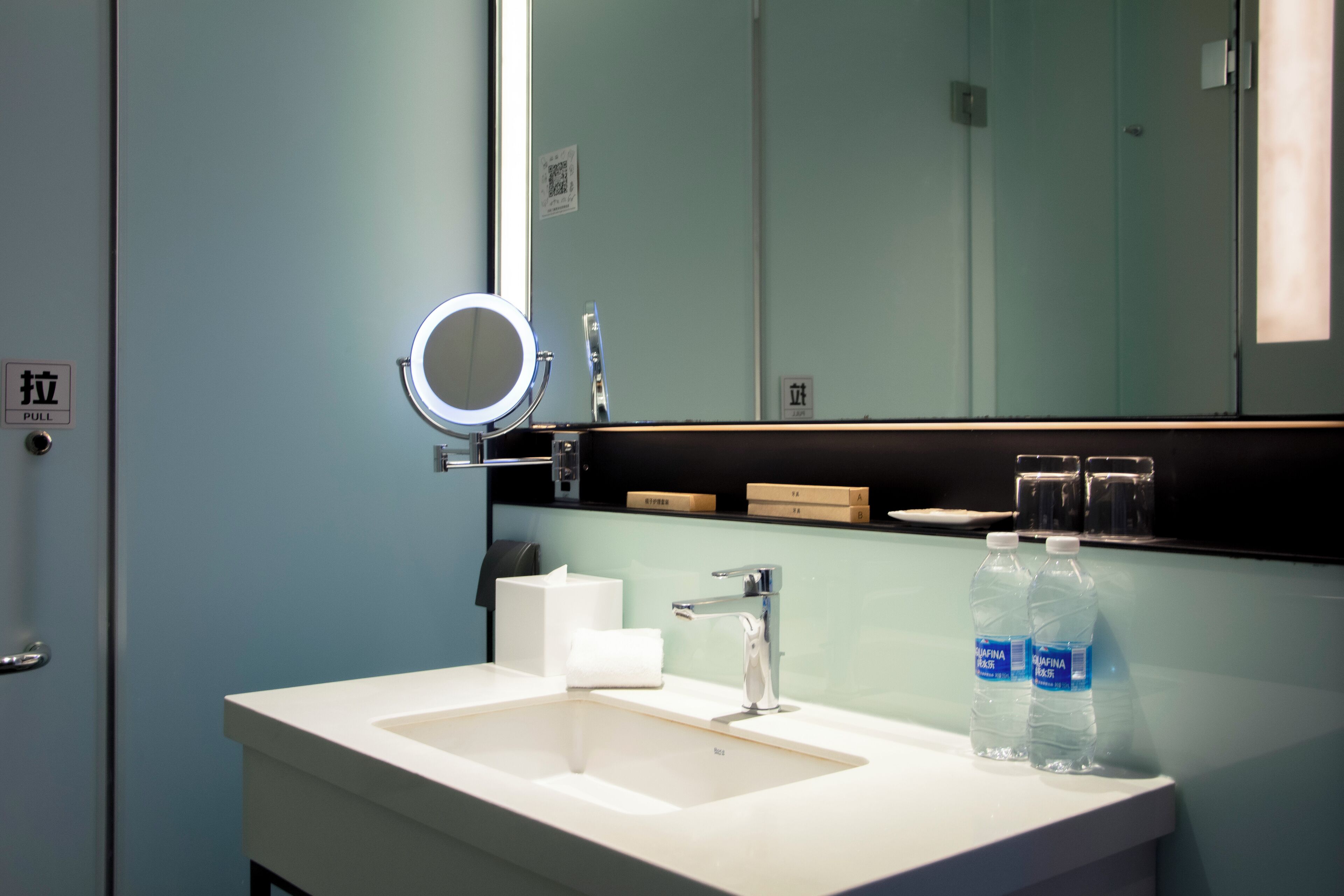 A bathroom with a sink, mirror, and two water bottles.