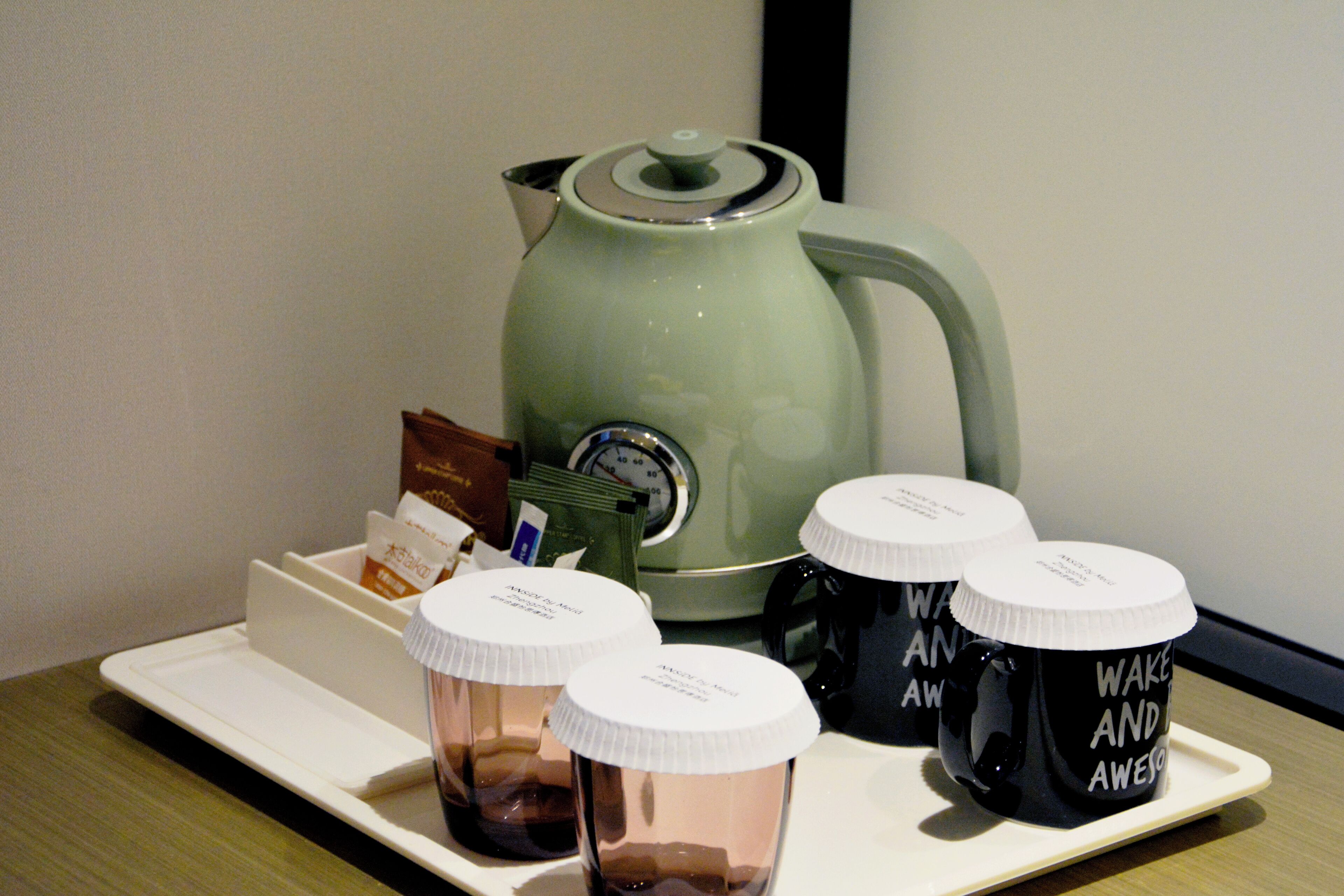 A tray with coffee mugs, a coffee pot, and tea packets on a table.