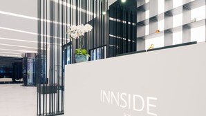 A modern reception area with a white reception desk labeled "INNSIDE BY MELIA". - INNSiDE by Meliá Zhengzhou (Zhengzhou)
