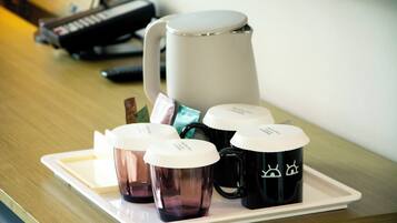 A tray with a coffee maker, several mugs, and a notebook on a wooden table.