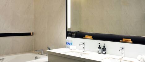 Un baño moderno con un espejo grande, una bañera y un tocador con dos lavabos.