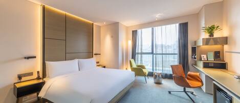 Een moderne hotelkamer met een groot bed, een bureau en een stoel. Er is een raam met uitzicht op de stad, en de kamer heeft een minimalistisch design.