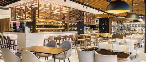 Un café moderno con paneles de techo de madera, una zona de bar y diferentes disposiciones de asientos.