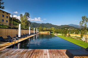 A swimming pool with a wooden deck, lounge chairs, and a view of mountains. - Podere La Torre (Schio)