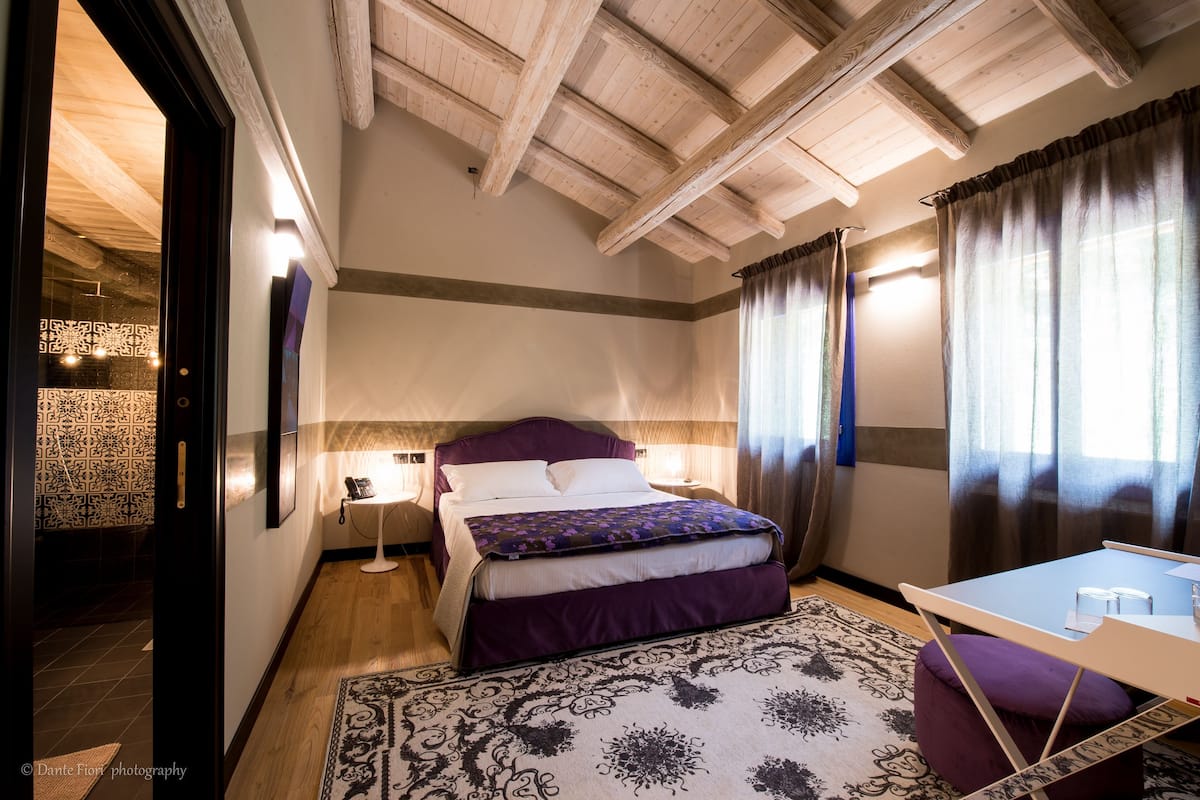 A bedroom with a bed, bedside tables, a desk, and a patterned rug.